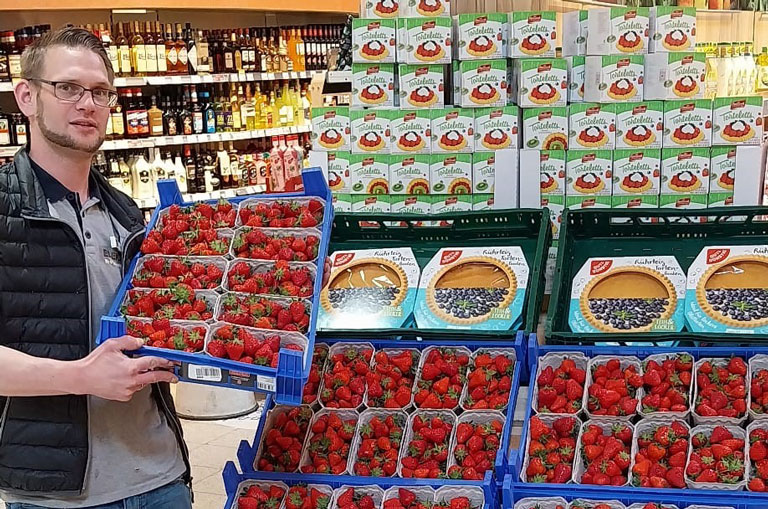 Kevin Bremer präsentiert im E-Center Lunze die frisch eingetroffenen Erdbeeren für die Kunden.